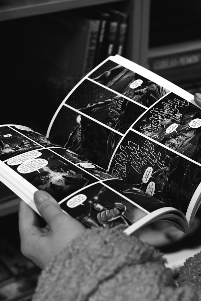 about-06 Black and white photo of a person reading a comic book, capturing detailed artwork.