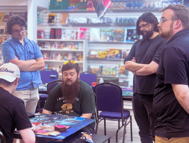 Group of people around a table watching a card tournament
