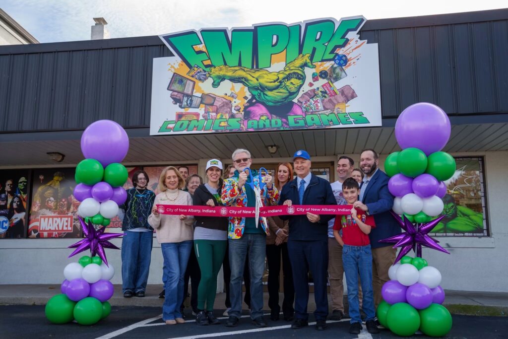 Empire Grand reopening Group of people posing in front of store with Empire Comics and Games Sign, there are purple and green balloons