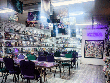 Game room Purple and green chairs around tables covered in colorful playmats, walls covered by board games